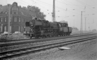 Dampflokomotive der BR 50 vor einigen Häusern. Die Lok fährt wahrscheinlich auf der Strecke der heutigen Glückaufbahn in Richtung Hbf Wanne-Eickel (in die Linkskurve). Dahinter links steht die Gaststätte/Kneipe mit den Aufschriften Haus Otto und Fiege-Pils und rechts weitere Wohngebäude am Bahnhaltepunkt Herne Rottbruch. Im Fotostandpunkt-Rücken müsste die A43 sein. Das Foto ist von 1968.[2]