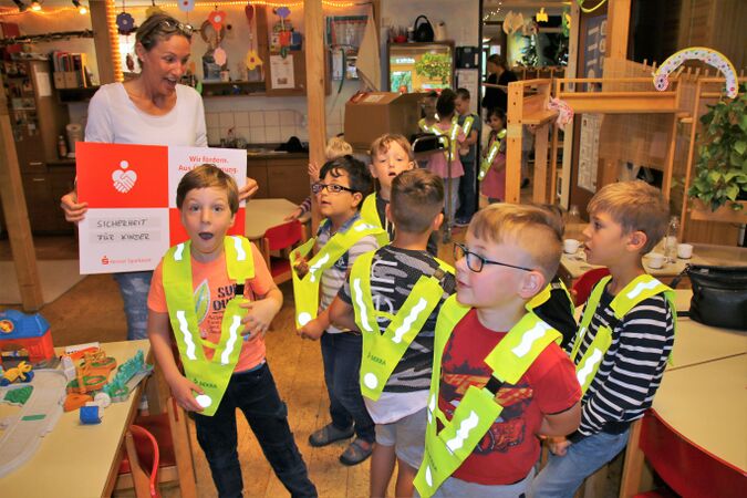 Erzieherin Doris Finking freut sich mit den Kindern über die neuen Warnwesten